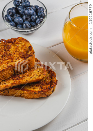 French toast on a white plate with blueberries and orange juice for breakfast 119216779