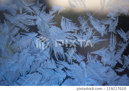 A closeup view showcasing the intricate and detailed frost patterns formed on glass surfaces A closeup view showcasing the intricate and detailed frost patterns formed on glass surfaces 119217028