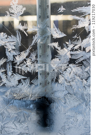 A thermometer is sitting on a frosty window, covered in ice crystals A thermometer is sitting on a frosty window, covered in ice crystals 119217030