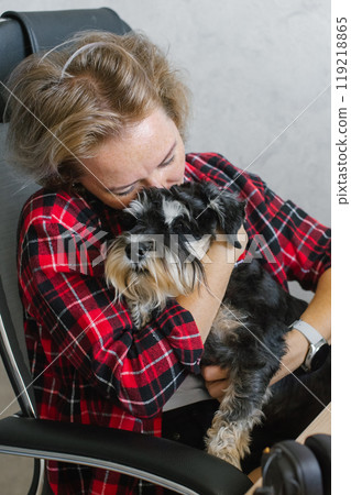 Woman Embracing her Small Dog at a Home Office Setting 119218865