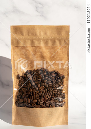 A kraft paper bag with coffee beans for viewing with a highlighted shadow lies on a white background 119218924