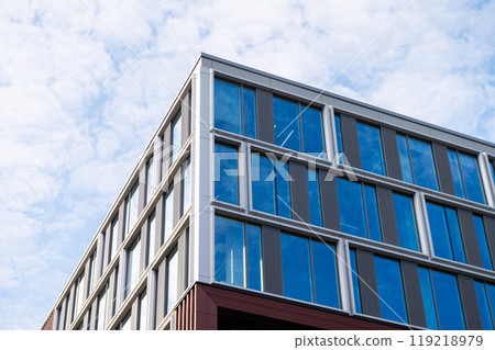 Low-angle view of a modern office building with glass windows against a blue sky Low-angle view of a modern office building with glass windows against a blue sky 119218979