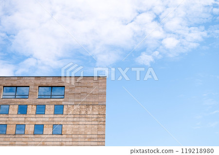 Modern building facade with large windows against blue sky with clouds. Modern building facade with large windows against blue sky with clouds. 119218980