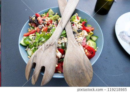 Fresh vegetable salad with tomatoes, cucumbers, seeds, and wooden salad servers. 119218985