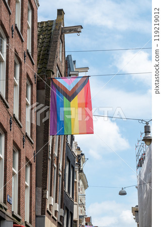Progress Pride flag with intersex symbol displayed on a building facade in an urban street. Progress Pride flag with intersex symbol displayed on a building facade in an urban street. 119219012