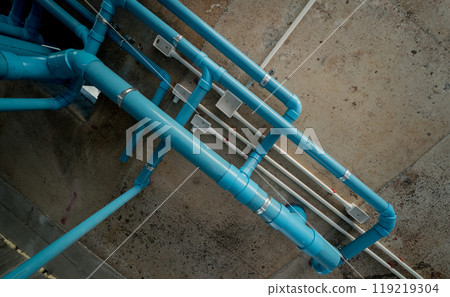 A bright blue pipes attached to a solid concrete wall A bright blue pipes attached to a solid concrete wall 119219304