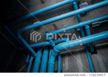 A bright blue pipes attached to a solid concrete wall 119219417