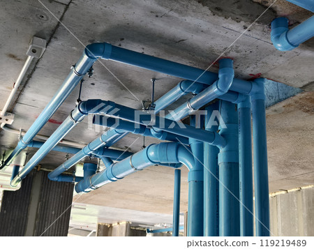 A bright blue pipes attached to a solid concrete wall A bright blue pipes attached to a solid concrete wall 119219489