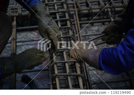 A group of builders is busy constructing a metal structure A group of builders is busy constructing a metal structure 119219490