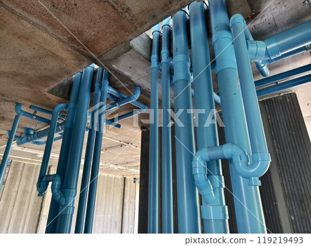 A bright blue pipes attached to a solid concrete wall 119219493