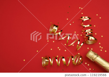 A stylish champagne bottle with gold streamers on a red background 119219566