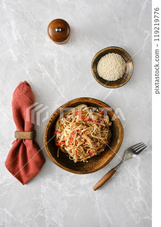 Homemade Asian stir-fried noodles with pulled beef and vegetables, served in a wooden bowl on a marble countertop Homemade Asian stir-fried noodles with pulled beef and vegetables, served in a wooden bowl on a marble countertop 119219776