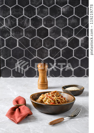 Delicious spaghetti with pulled beef and fresh ingredients served in a rustic bowl on a marble countertop 119219778