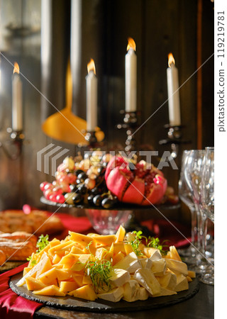 An inviting cheese platter with fruits and candles set for a cozy evening gathering An inviting cheese platter with fruits and candles set for a cozy evening gathering 119219781