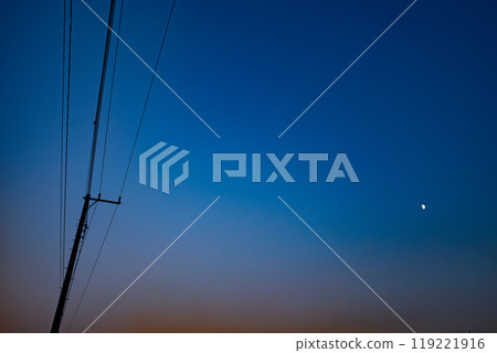 A cloudless magic hour sky and a half moon 119221916