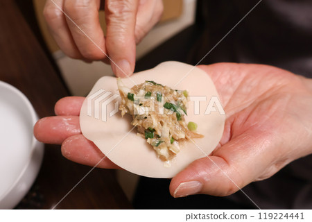An elderly woman wrapping dumpling filling in gyoza skins An elderly woman wrapping dumpling filling in gyoza skins 119224441