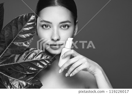 Close up woman face with green exotic leaf 119226017