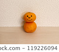 A mandarin orange daruma with a painted face 119226094