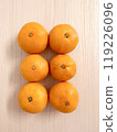 Six mandarins lined up on a table 119226096