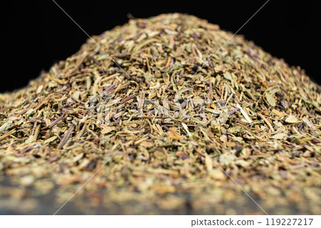 Pile of chopped dry basil seasoning on a black background. 119227217