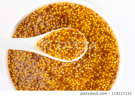 Traditional French Dijon mustard in a spoon on a white background Traditional French Dijon mustard in a spoon on a white background 119227232
