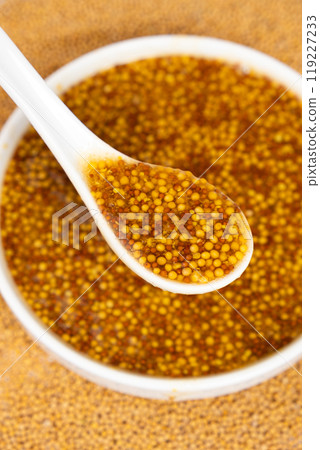 Traditional French Dijon mustard in a spoon on a white background Traditional French Dijon mustard in a spoon on a white background 119227233
