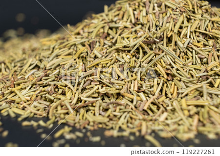 Pile of chopped dry rosemary seasoning on a black background. 119227261