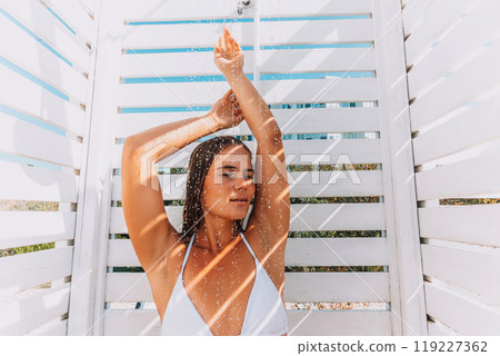 A woman is standing in front of a structure with a shower., with her arms raised and her hair blowing in the wind. She is enjoying the moment and taking in the beauty of her surrounding A woman is standing in front of a structure with a shower., with her arms raised and her hair blowing in the wind. She is enjoying the moment and taking in the beauty of her surrounding 119227362