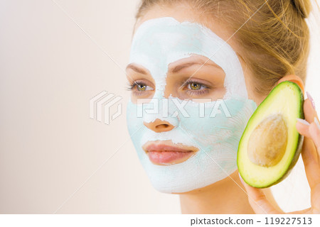 Girl facial mud mask holds avocado fruit Girl facial mud mask holds avocado fruit 119227513