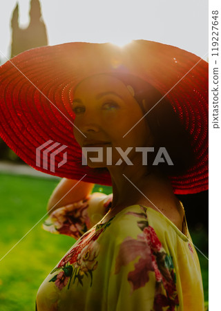 Portrait of a woman wearing a large red sun hat during golden hour 119227648