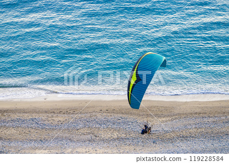 Paraglider flying over sea shore 119228584