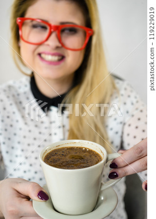 Happy woman at office drinking hot coffee 119229019