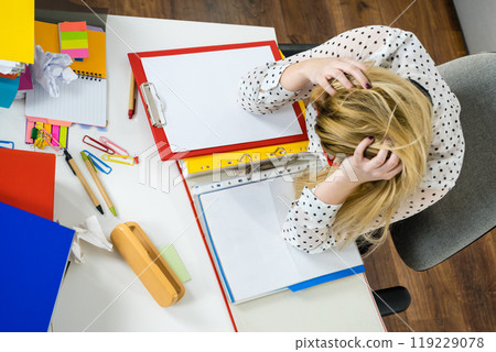 Depressed businesswoman sitting at desk 119229078