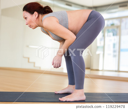 Pregnant woman is engaged in yoga. Uttanasana or Standing Forward Bend 119229478