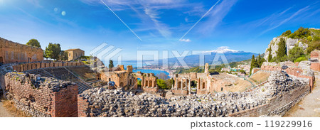 Panoramic view of ruins of Ancient Greek theatre in Taormina on background of Etna Volcano, Italy. Panoramic view of ruins of Ancient Greek theatre in Taormina on background of Etna Volcano, Italy. 119229916