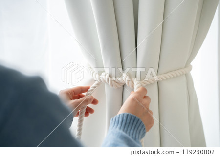 Hands tying up curtains Hands tying up curtains 119230002