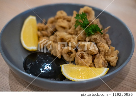 Close-up photo of Fried Squid or Calamari with lemon served on plate. 119230926