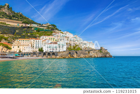 Beautiful Amalfi on hills leading down to coast, comfortable beaches and azure sea on Amalfi Coast in Campania, Italy Beautiful Amalfi on hills leading down to coast, comfortable beaches and azure sea on Amalfi Coast in Campania, Italy 119231015