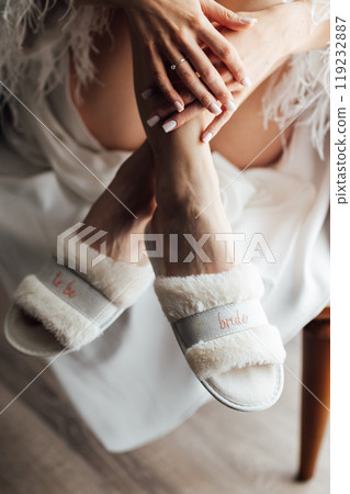 Wedding morning. The bride shows slippers with the inscription bride on her slender legs 119232887