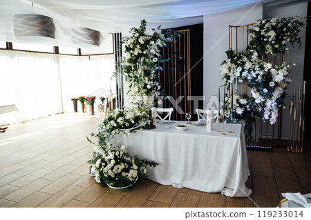 Luxurious restaurant. Luxurious interior, white tables, serving dishes and glasses for guests Luxurious restaurant. Luxurious interior, white tables, serving dishes and glasses for guests 119233014