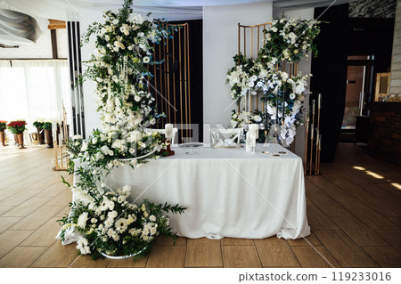 Luxurious restaurant. Luxurious interior, white tables, serving dishes and glasses for guests Luxurious restaurant. Luxurious interior, white tables, serving dishes and glasses for guests 119233016
