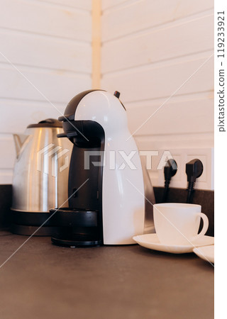 Modern kitchen coffee setup with a white coffee machine and cups, ready for a fresh morning brew 119233921
