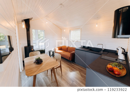 Modern open-concept kitchen and living area with natural light, cozy seating, and warm wooden design Modern open-concept kitchen and living area with natural light, cozy seating, and warm wooden design 119233922