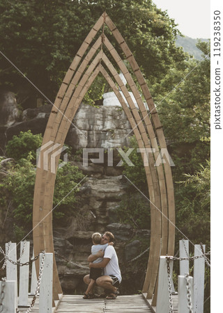 Vintage matte effect photo. Happy lifestyle moment. Man crouched, gesture hand, look into eyes each other listen boy walk funny play. Father hug hold child son closely arm embrace, fatherhood love 119238350