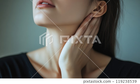 Young woman is posing with her hand gently touching her neck, her expression is serene and peaceful. Her perfect skin and delicate features evoke a sense of tranquility and well being 119238539