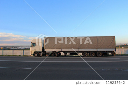 Long truck on a highway near the fence of the transport airport with planes 119238642