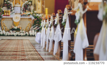 Lida, Belarus - June 15, 2021: Wooden church benches decorated with flowers for first communion ceremony Lida, Belarus - June 15, 2021: Wooden church benches decorated with flowers for first communion ceremony 119238770