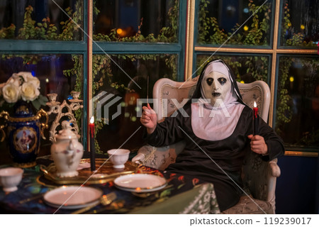 Scary halloween nun hold knife and candle at dinner food table Scary halloween nun hold knife and candle at dinner food table 119239017
