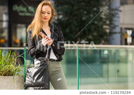 Casual girl walking in city with mobile phone 119239284