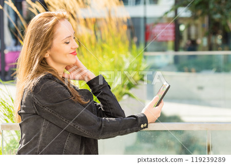 Girl using mobile phone on city street Girl using mobile phone on city street 119239289